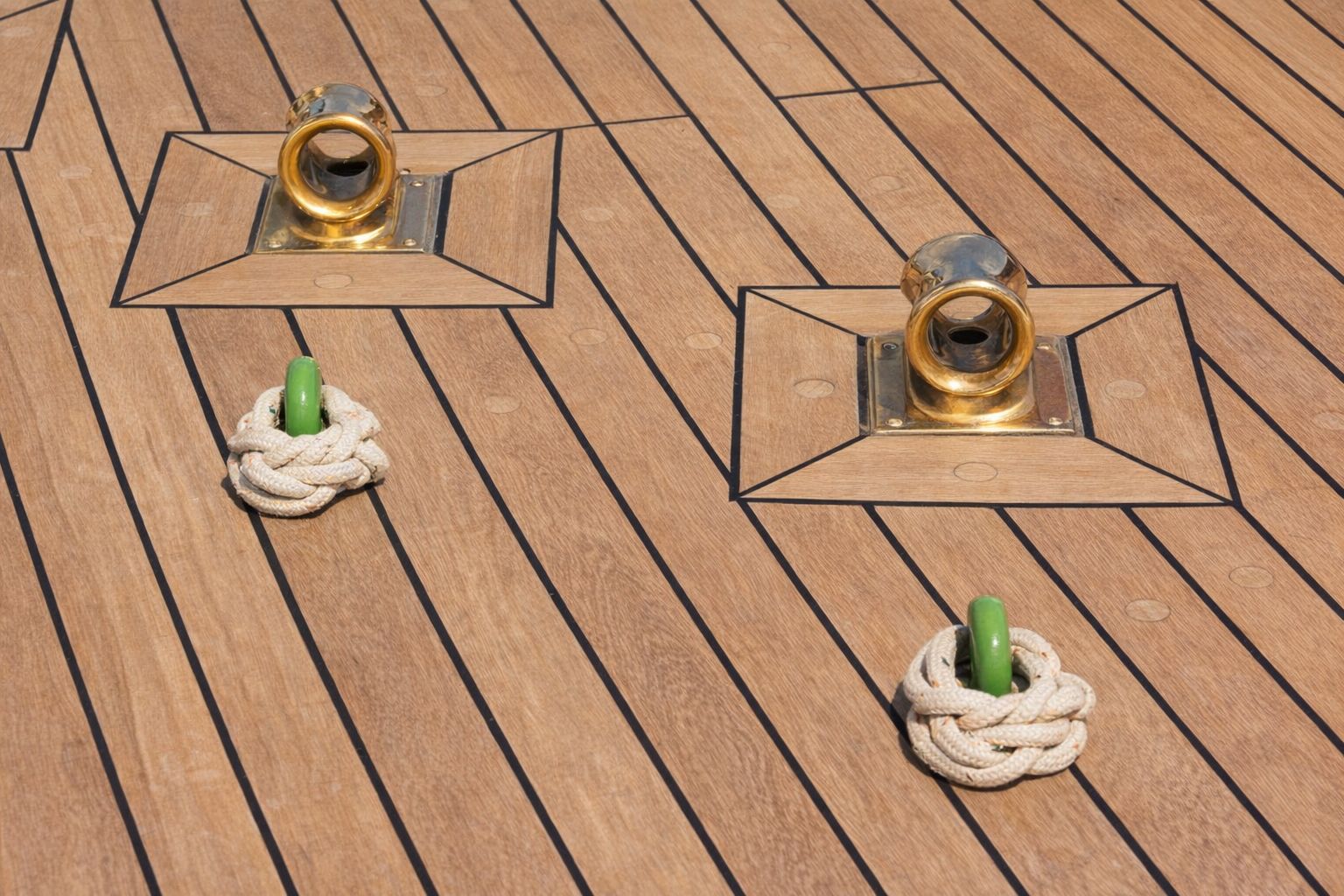 Gnistrande mässingsbeslag och rep på ett välskött teakdäck till en lyxyacht.
