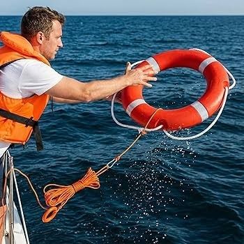 Man i flytväst kastar en livboj med lina i havet